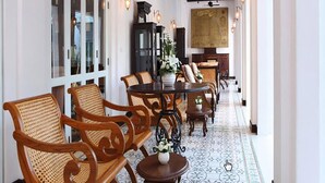 A corridor with wooden chairs and tables, a patterned floor, and a large map on the wall.
