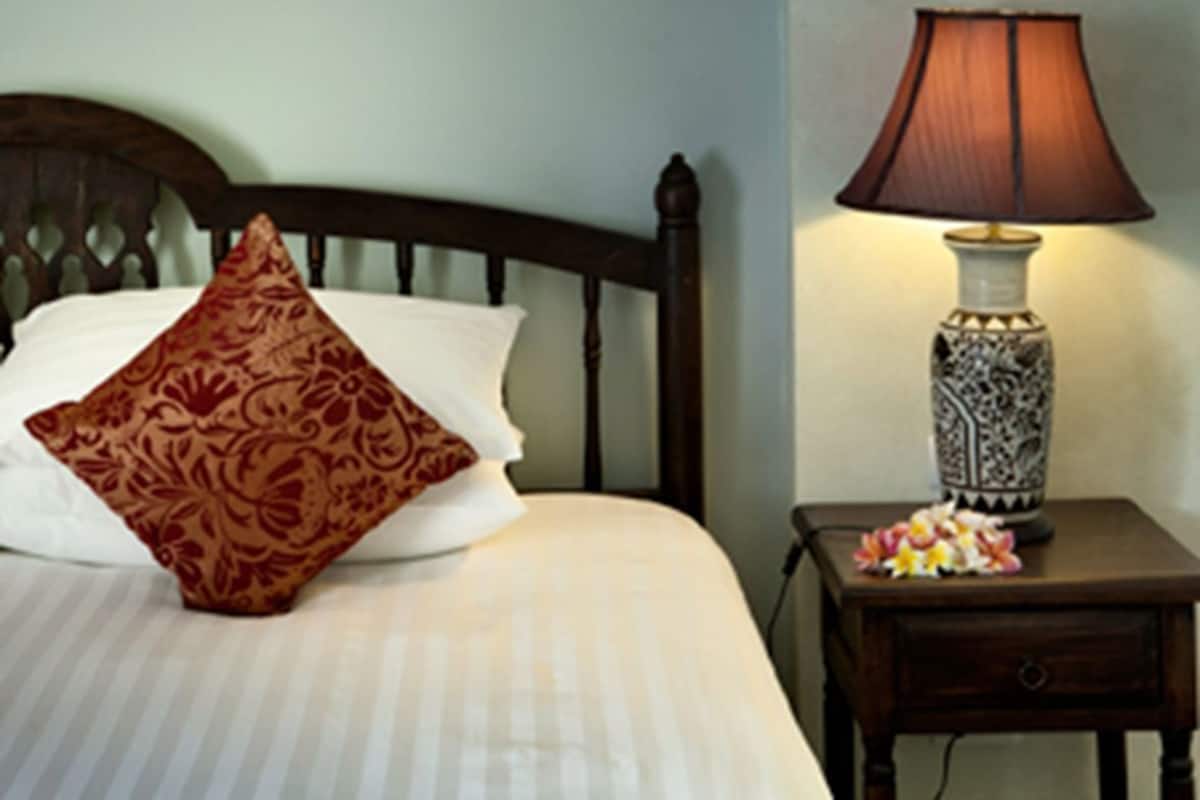 Une chambre à coucher comprenant un lit, une fresque murale décorative, une lampe de chevet et une table de chevet avec un vase.
