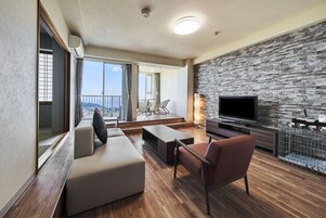A modern living room with a large TV, a stone wall, and a balcony with a view.