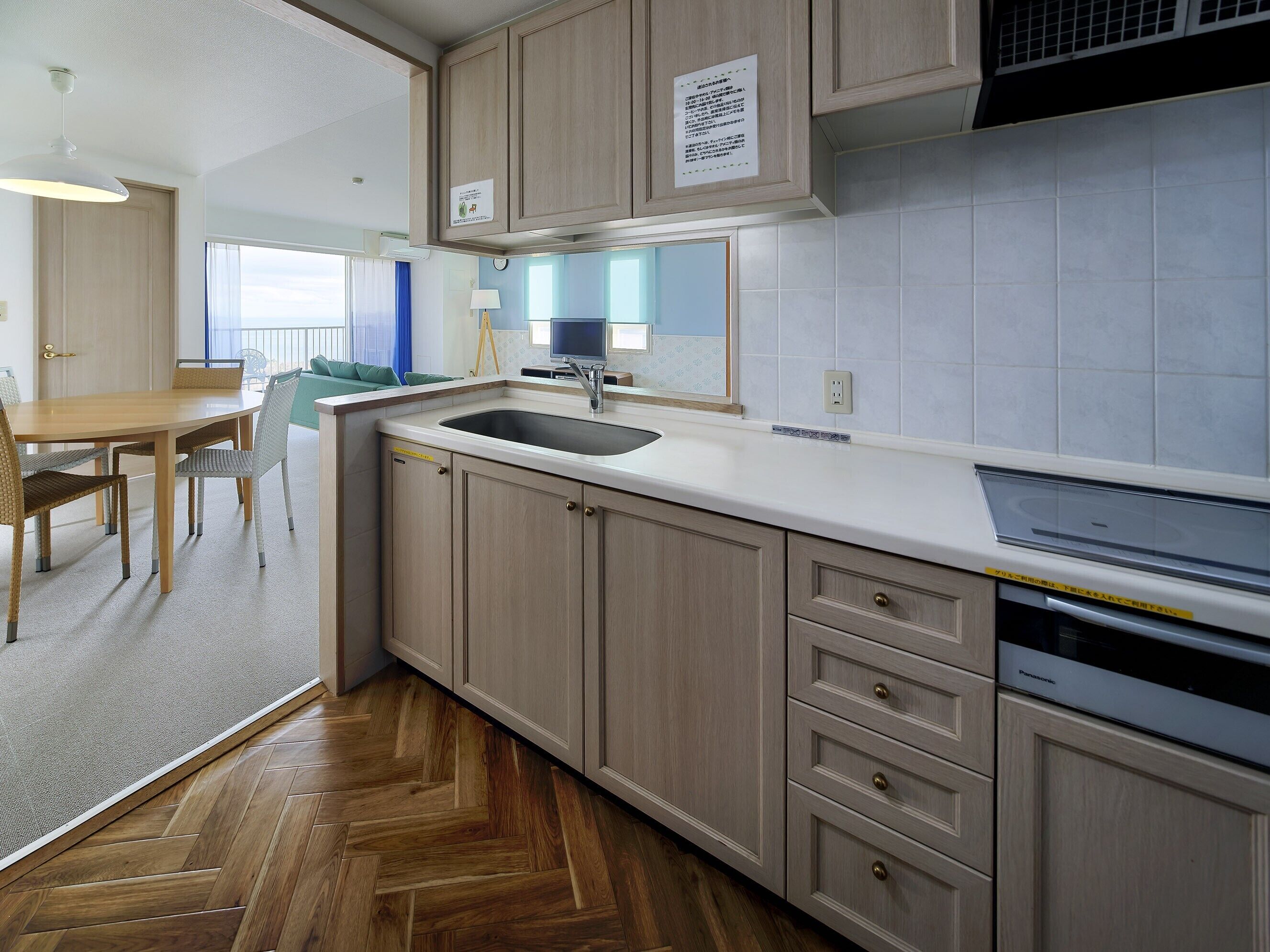 A modern kitchen with wooden cabinets, a sink, and a dining area with a table and chairs.