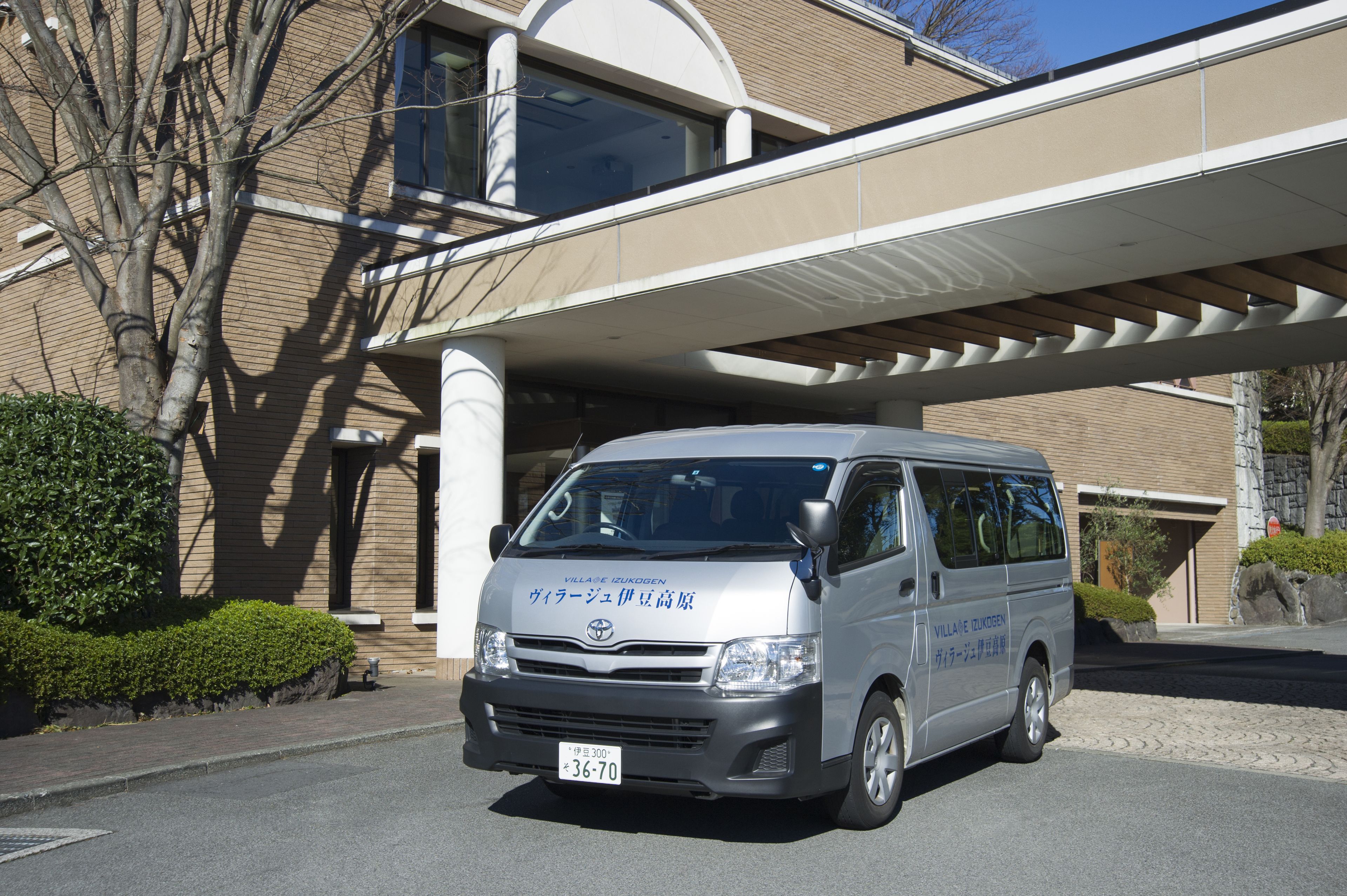 A silver van parked in front of a building with a covered walkway.