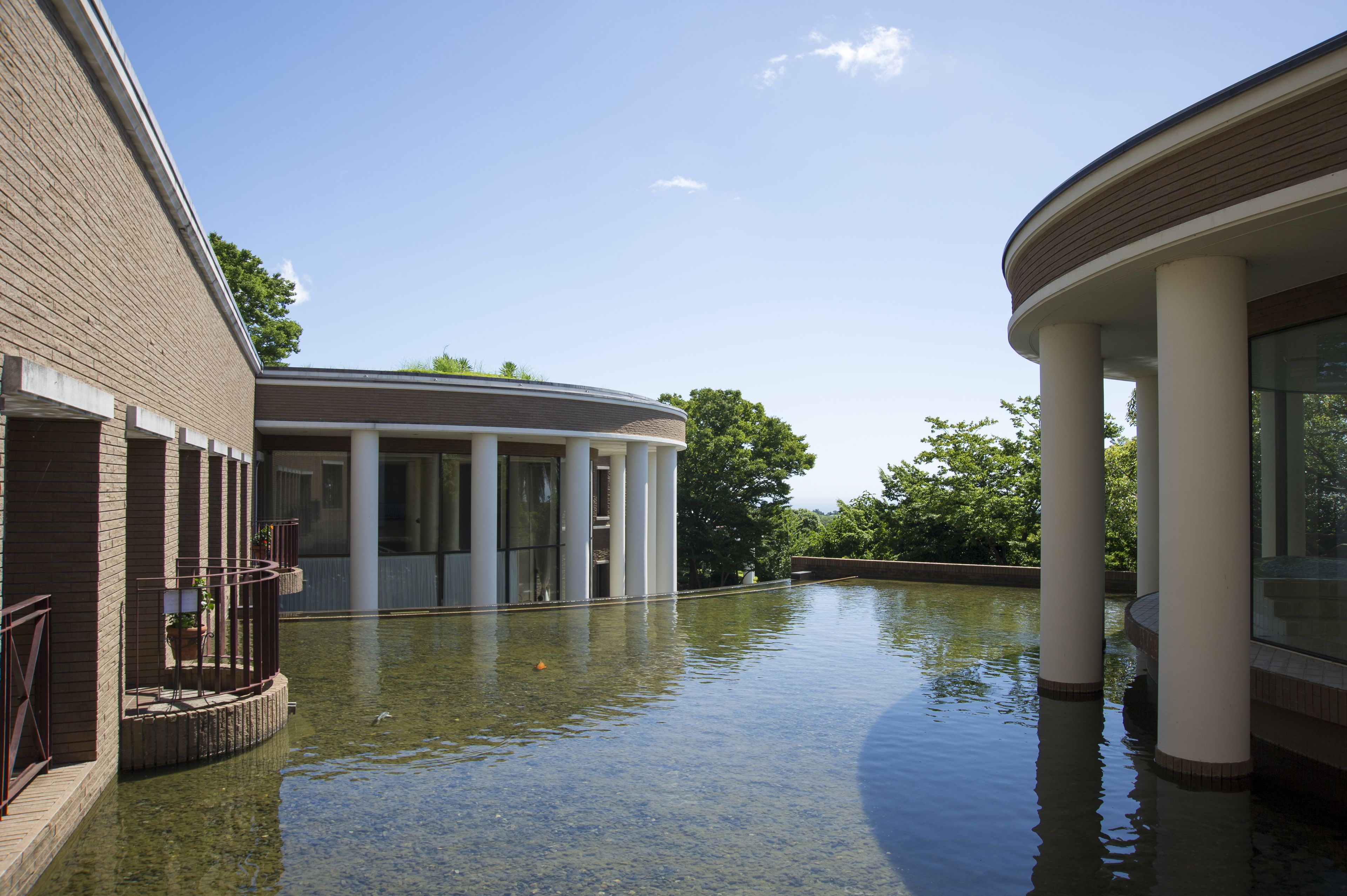 Un bâtiment avec une fontaine à l’avant, des colonnes et un ciel dégagé.