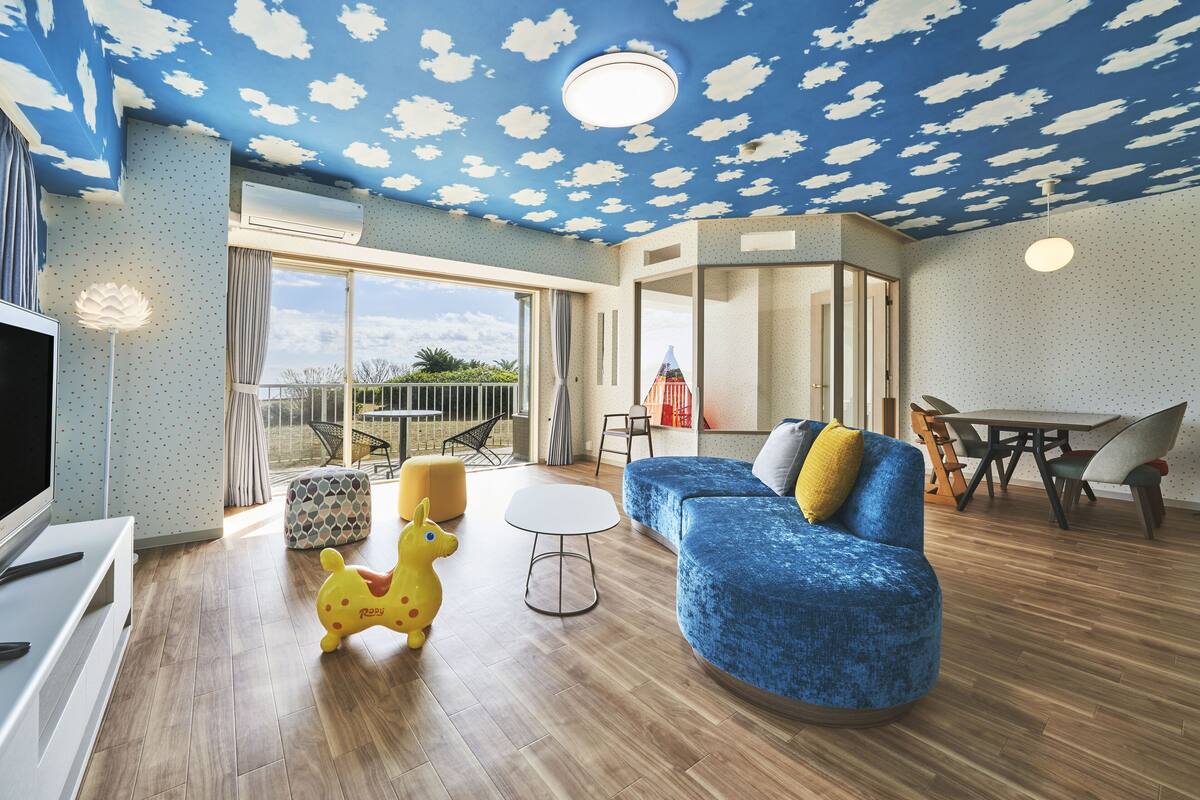 Un salon avec un canapé bleu, un jouet jaune et une table basse blanche.