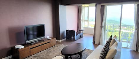 Een moderne woonkamer met een flatscreen televisie, bank, salontafel en een balkon met uitzicht.