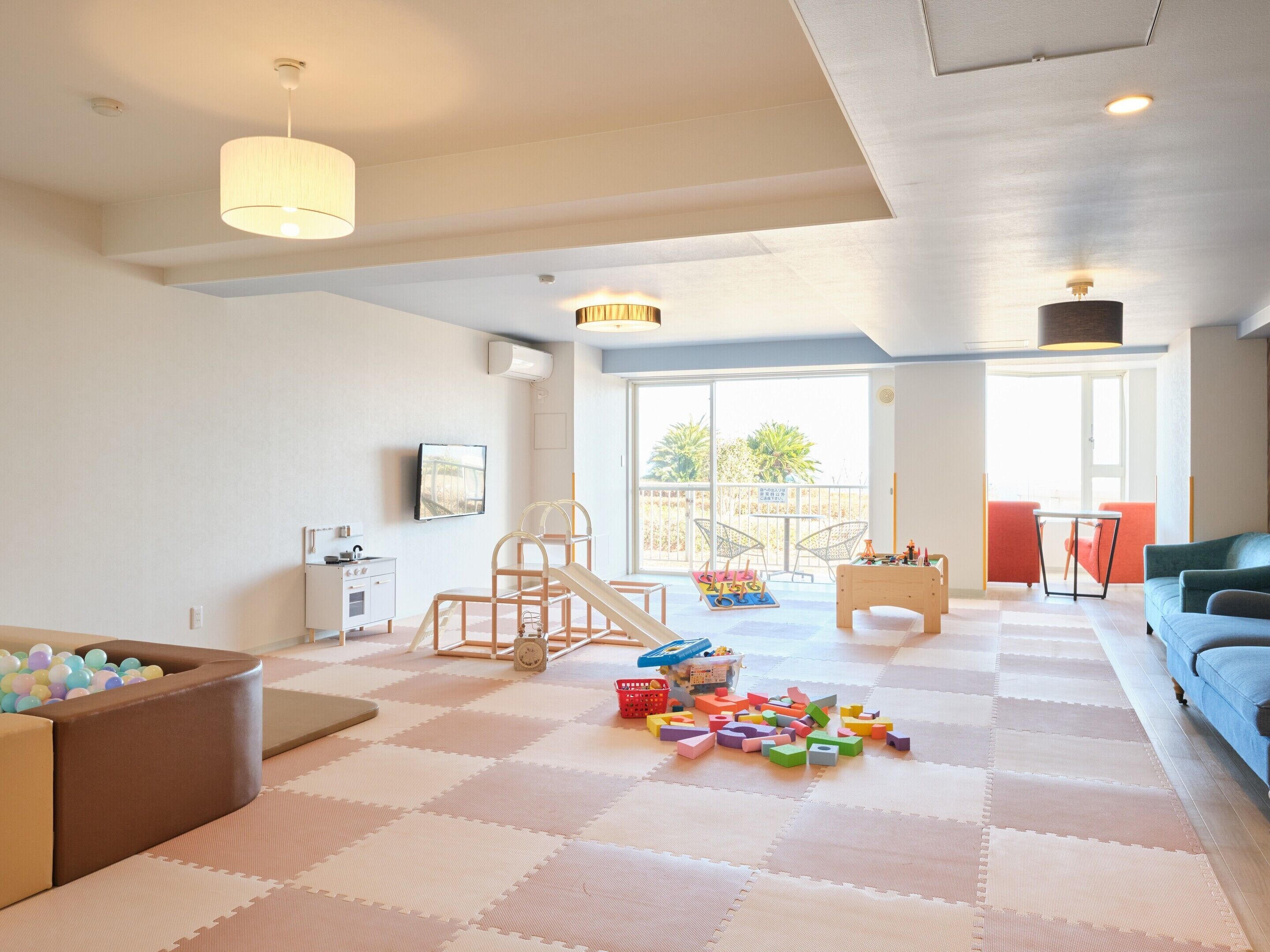 A spacious living room with a play area, a sofa, a coffee table, and a view of the outdoors.