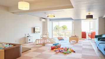 A spacious living room with a play area, a sofa, a coffee table, and a view of the outdoors.