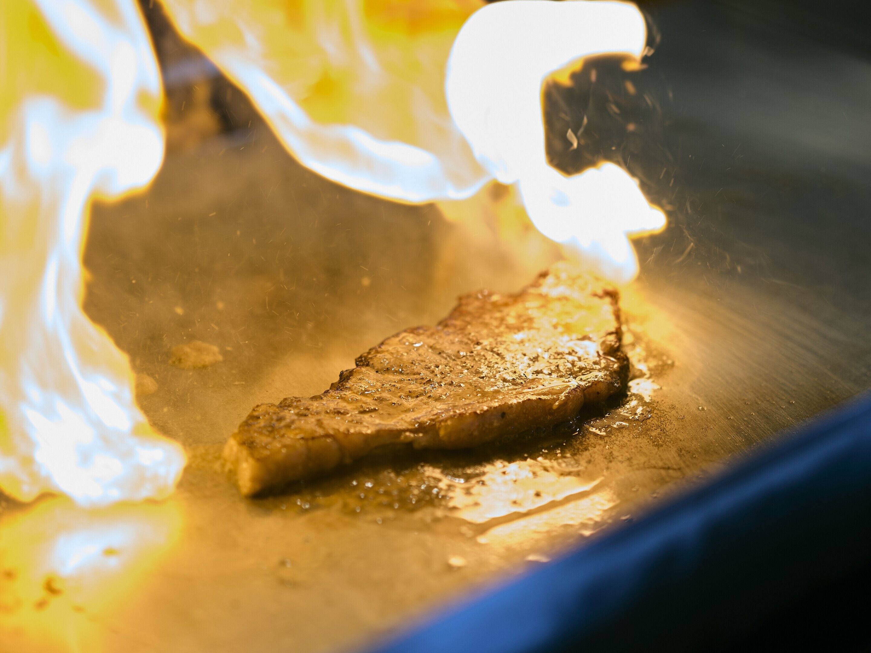 A steak being grilled on a pan.
