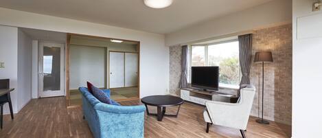 A modern living room with a flat-screen TV, two sofas, a coffee table, and a brick-patterned wall.