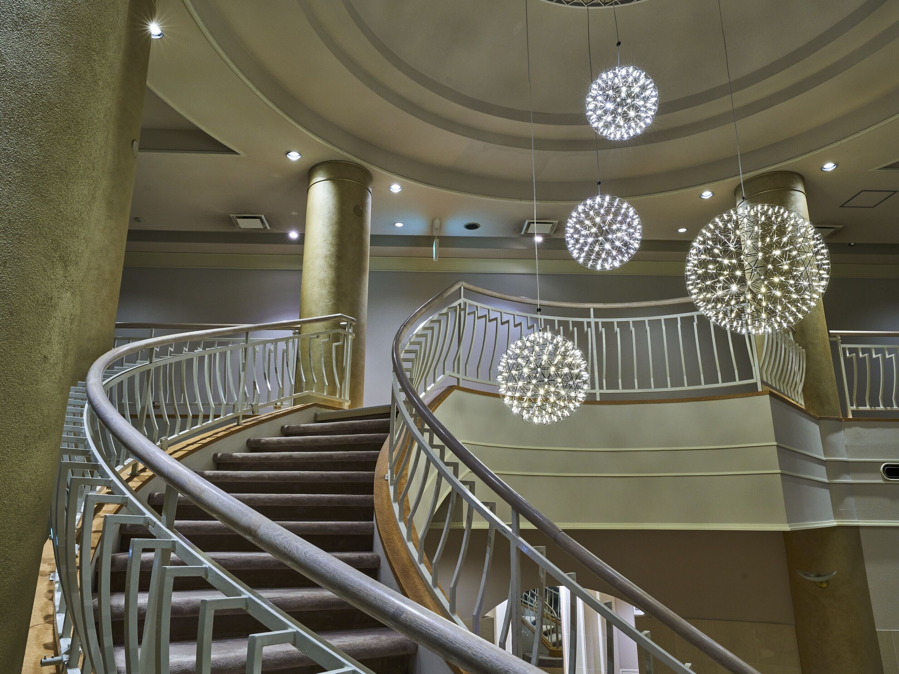 A spiral staircase with metal railings and a modern chandelier.