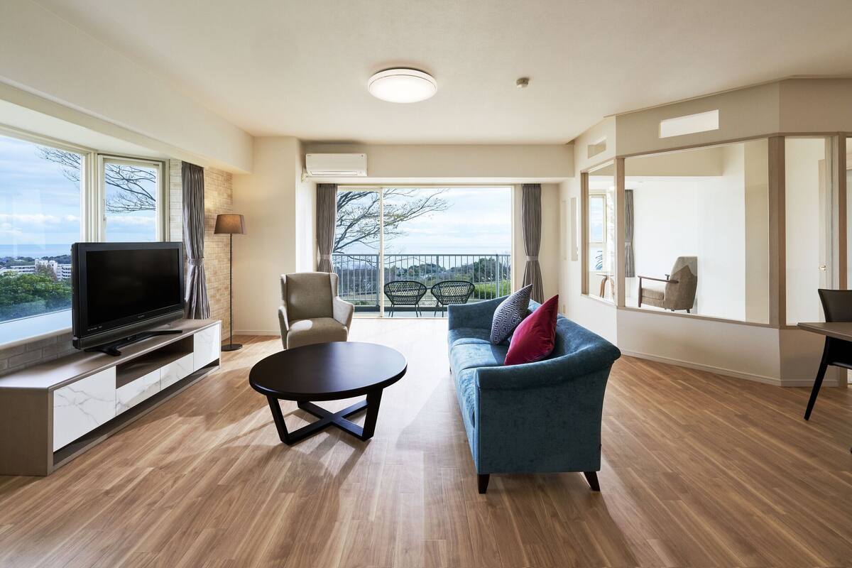 Un salon moderne doté d’un téléviseur à écran plat, d’un canapé, d’une table basse et d’un balcon offrant une vue agréable.