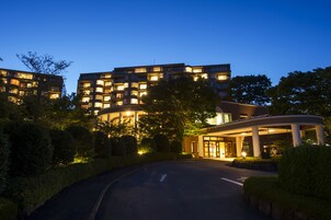 A modern hotel with multiple floors, a well-lit entrance, and a landscaped driveway.