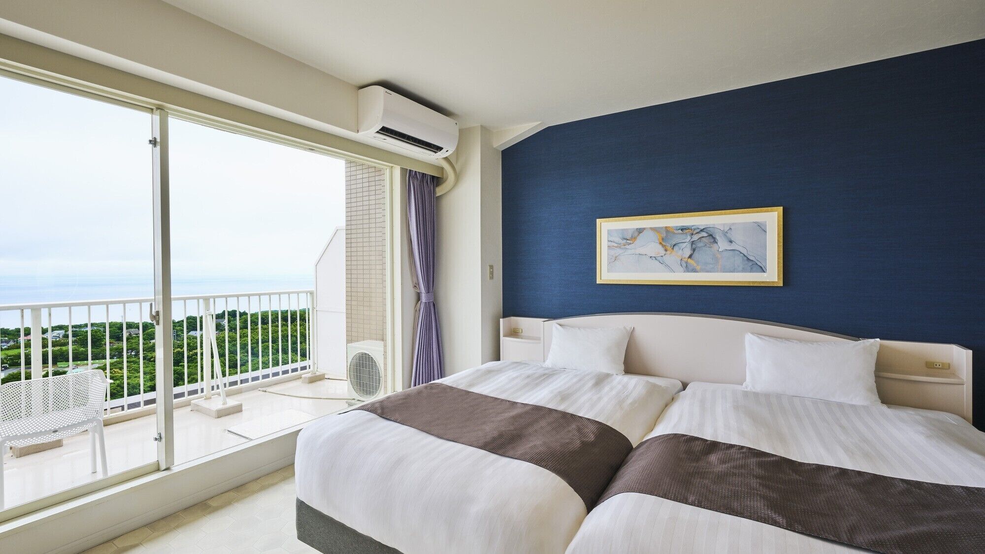 Een hotelkamer met een bed, uitzicht op groen en een balkon.