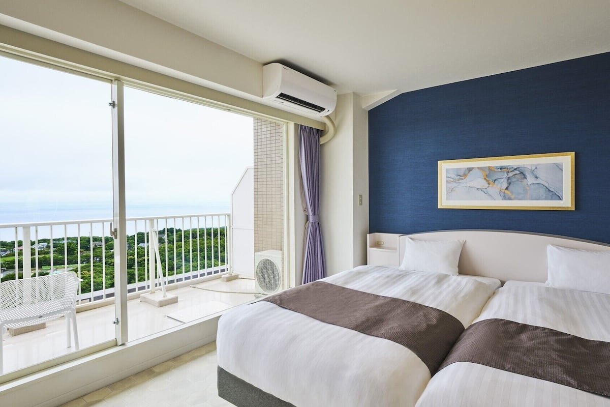 Une chambre d’hôtel avec un lit, une vue sur la verdure et un balcon.