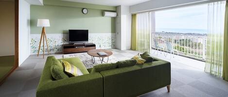A modern living room with a green sofa, a coffee table, and a flat-screen TV on a wooden stand.