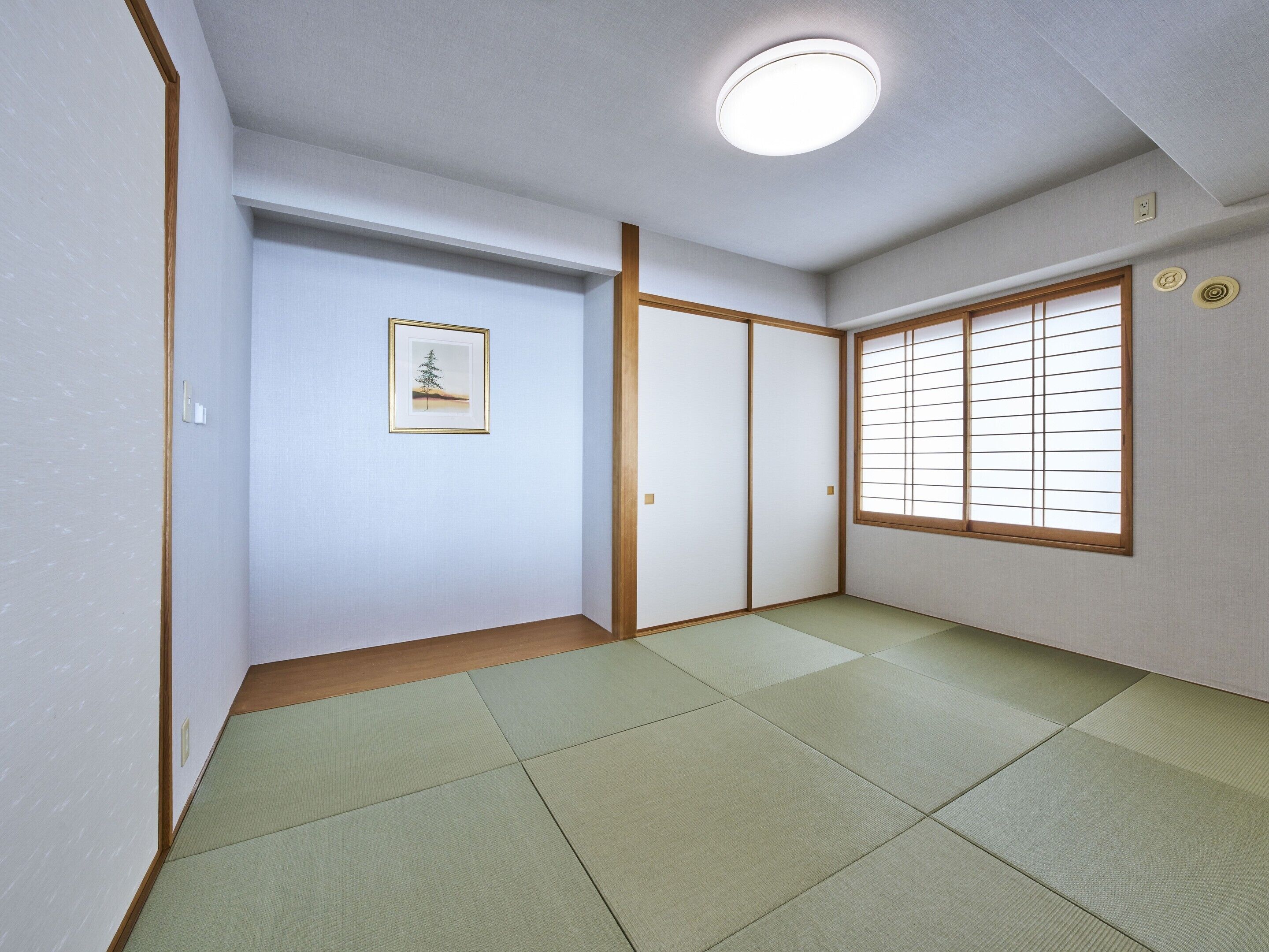 A room with tatami flooring, a shoji screen, and a framed picture on the wall.