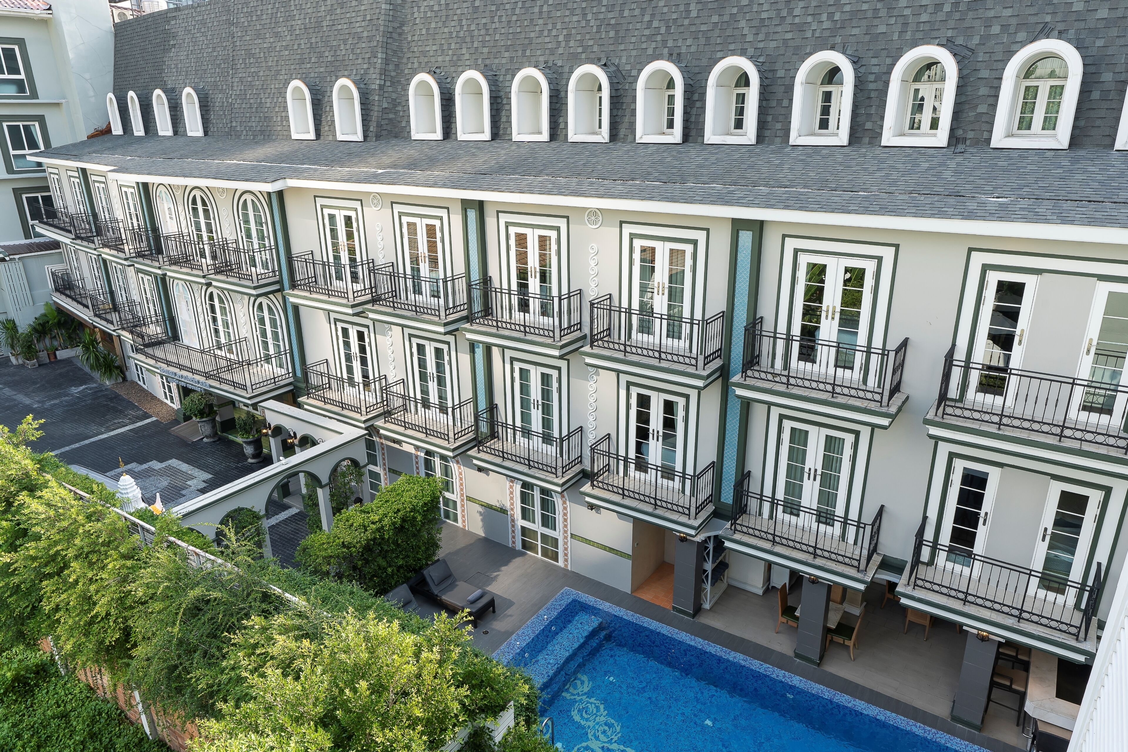 Un hotel de varios pisos con balcones, piscina y patio.