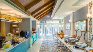 A hotel breakfast area with a long counter, buffet with various food items, and a view of the outside through large windows. -  La Petite Salil Sukhumvit Thonglor 1 (Bangkok)