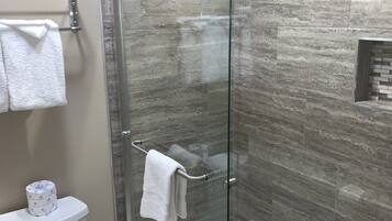Un baño moderno con ducha de vidrio, inodoro y toallero.