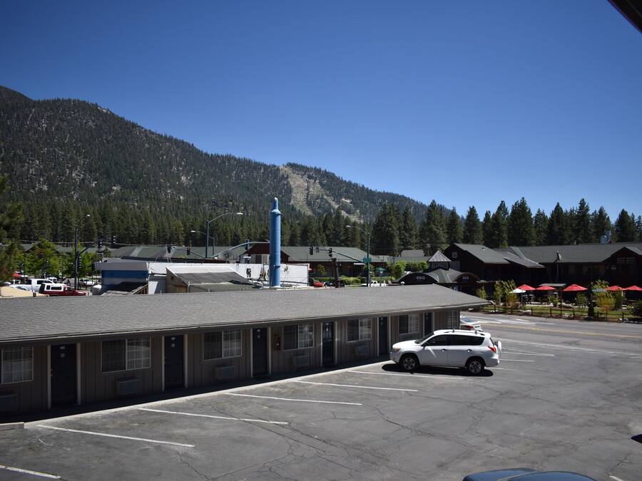 Ein Motel mit Parkplatz, einem Berg im Hintergrund und einigen Gebäuden mit roten Sonnenschirmen.