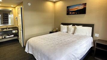 Ein Hotelzimmer mit einem großen Bett, einem Nachttisch, einem Spiegel und einem Bild an der Wand.