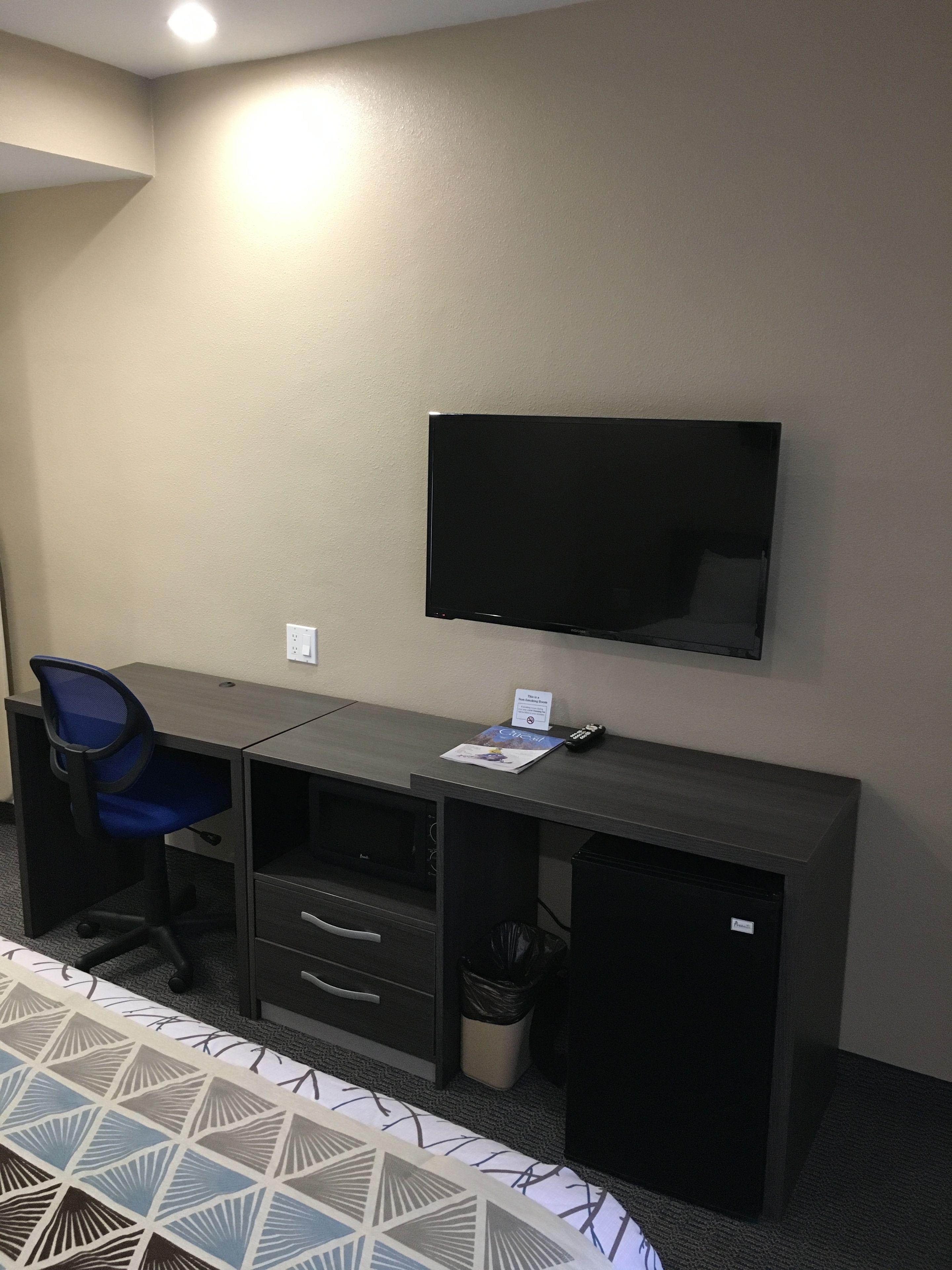 Une chambre d’hôtel équipée d’un bureau, d’une chaise, d’une télévision et d’un lit avec une couvre-lit à motifs.