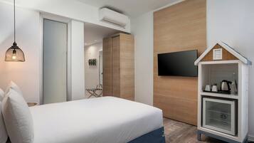 A bedroom with a bed, a TV mounted on the wall, a wardrobe, and a small cabinet with a glass door.