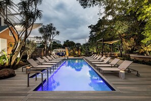 Ein Poolbereich mit Liegestühlen, einem Pool und umgebender Bepflanzung.