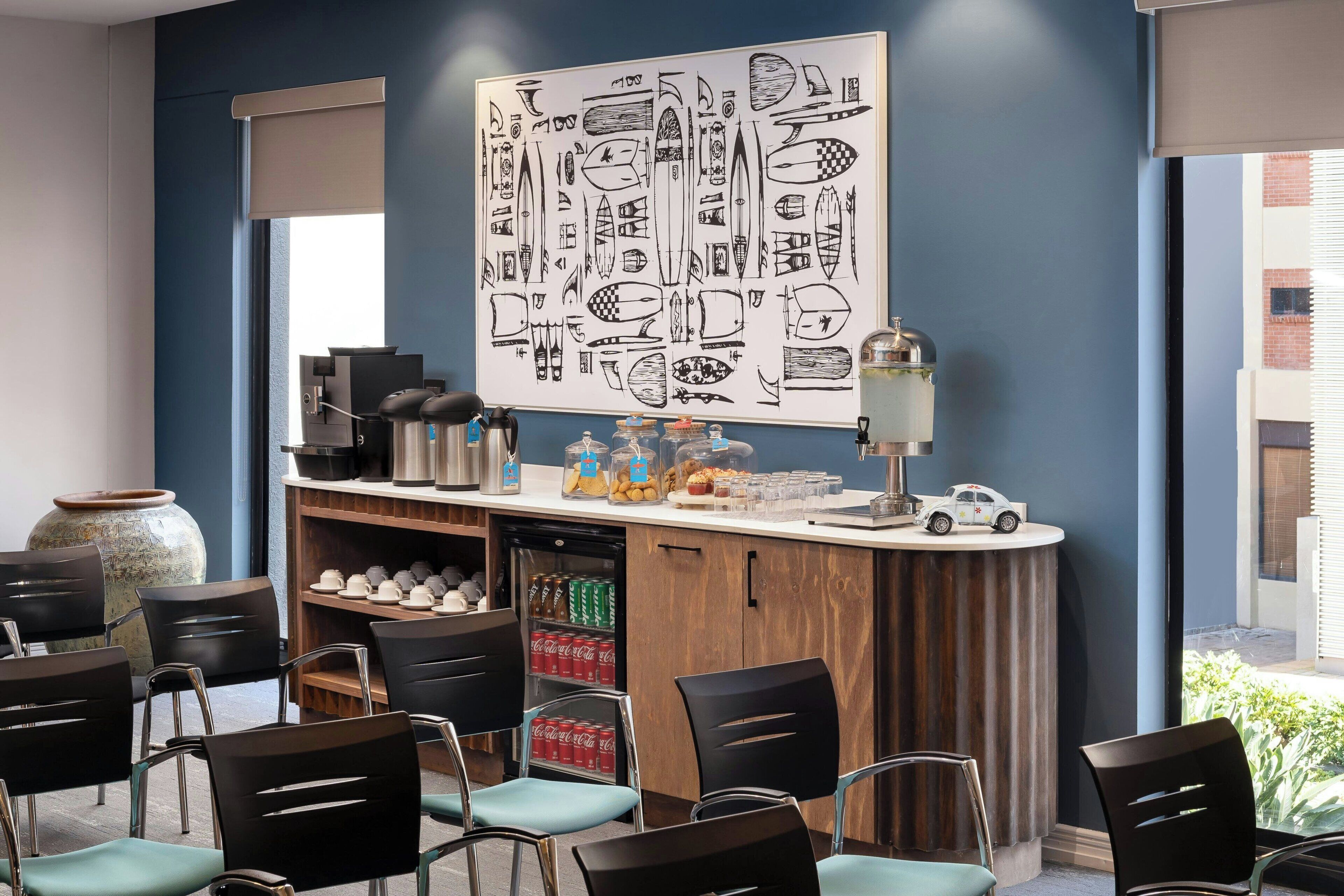 Een moderne barruimte met een groot zwart-wit kunstwerk met een nautisch thema, een koffieapparaat en een kleine autootje op de toonbank.