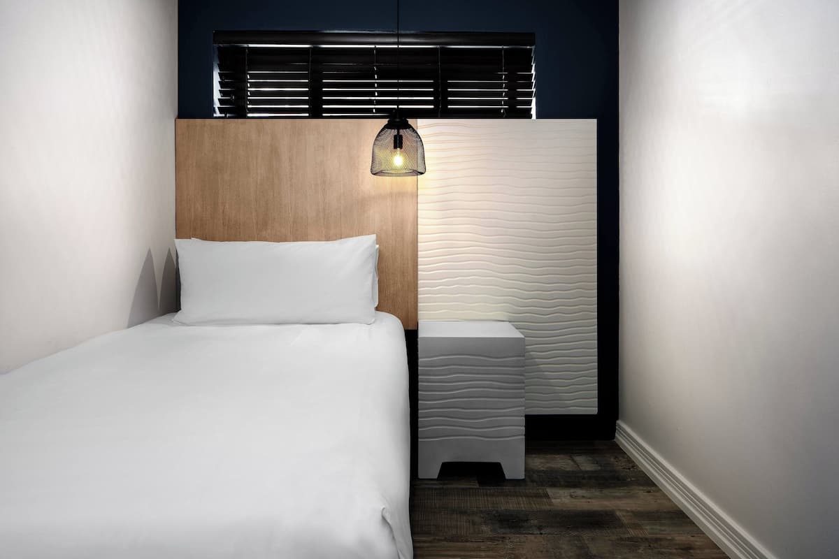 A bedroom with a wooden headboard, a bedside table, and a unique textured wall.