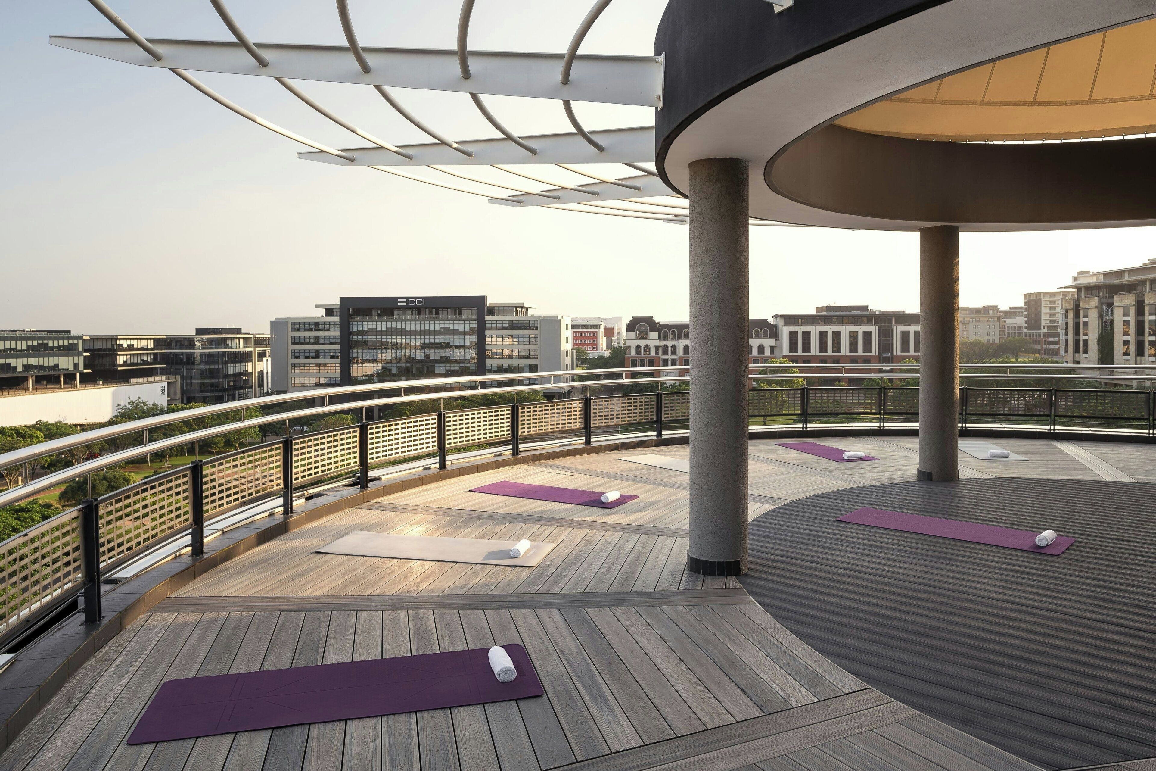 Una terraza exterior con piso de madera, colchonetas de ejercicio y barandilla.