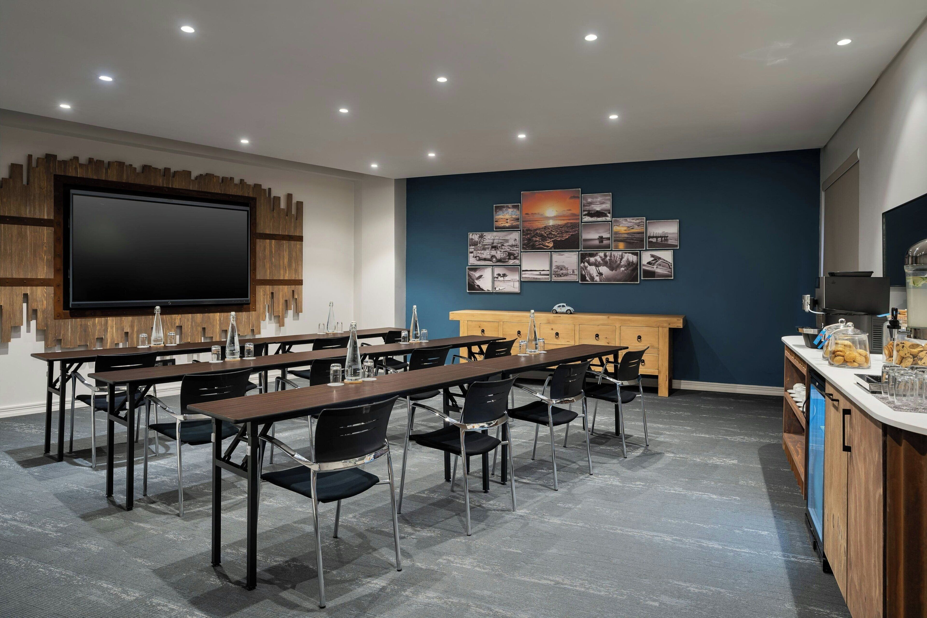 A conference room with a large flat-screen TV, wooden panel wall, and a wall of framed photographs.