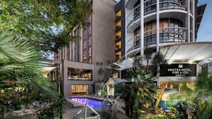 Hotel com piscina, área de estar externa e vegetação exuberante.