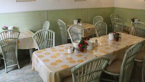 Zona de menjador amb taules rodones cobertes amb estovells grocs i blancs, i cadires de vimet.