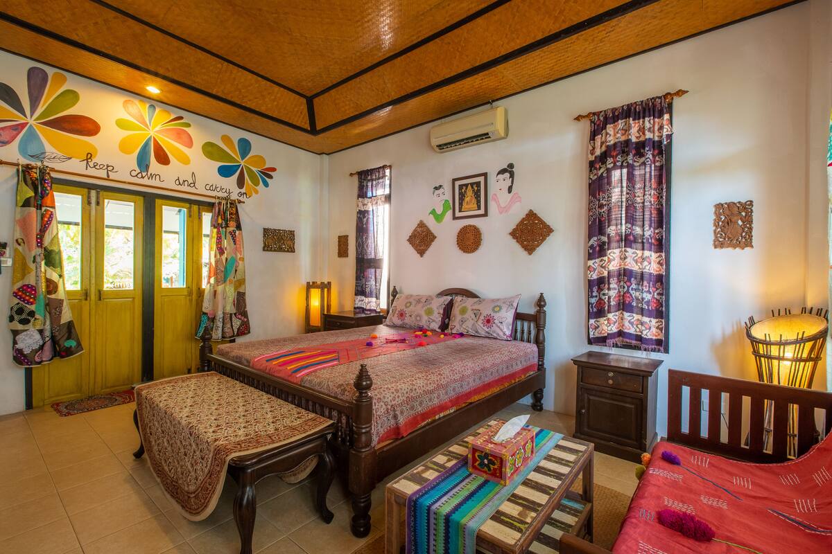 Ein gemütliches Schlafzimmer mit einem hölzernen Bett, einer Bank, einem Nachttisch und einem kleinen Schrank.