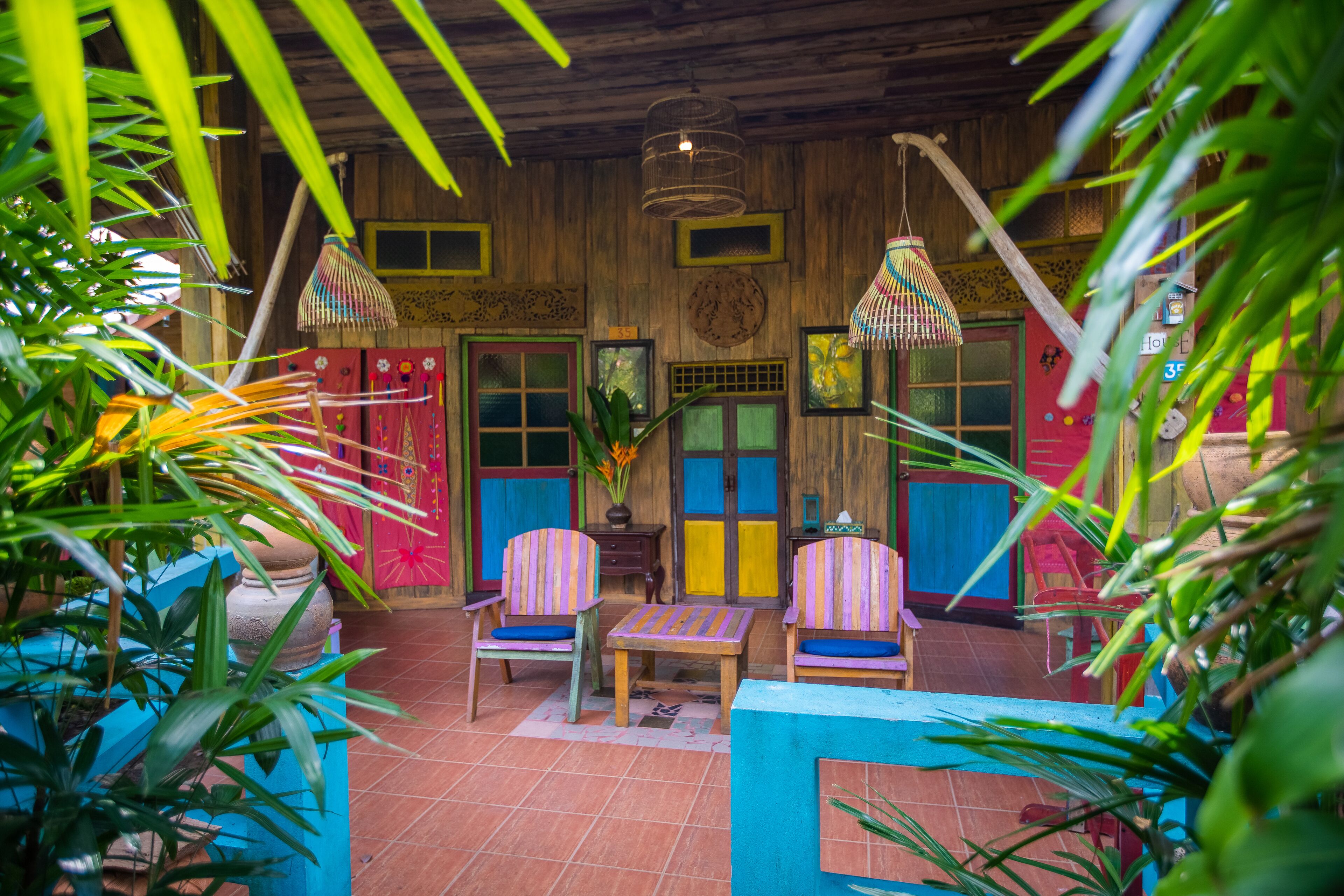 Un intérieur en bois, avec des chaises colorées et une table, le tout agrémenté de plantes.