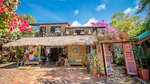 A colorful outdoor café with a thatched roof, surrounded by lush greenery and vibrant flowers. - Varinda Garden Resort (Koh Samui)