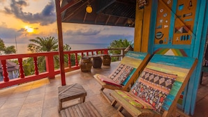 A wooden deck with a red railing, a wooden table, and two colorful lounge chairs with patterned cushions. - Varinda Garden Resort (Koh Samui)