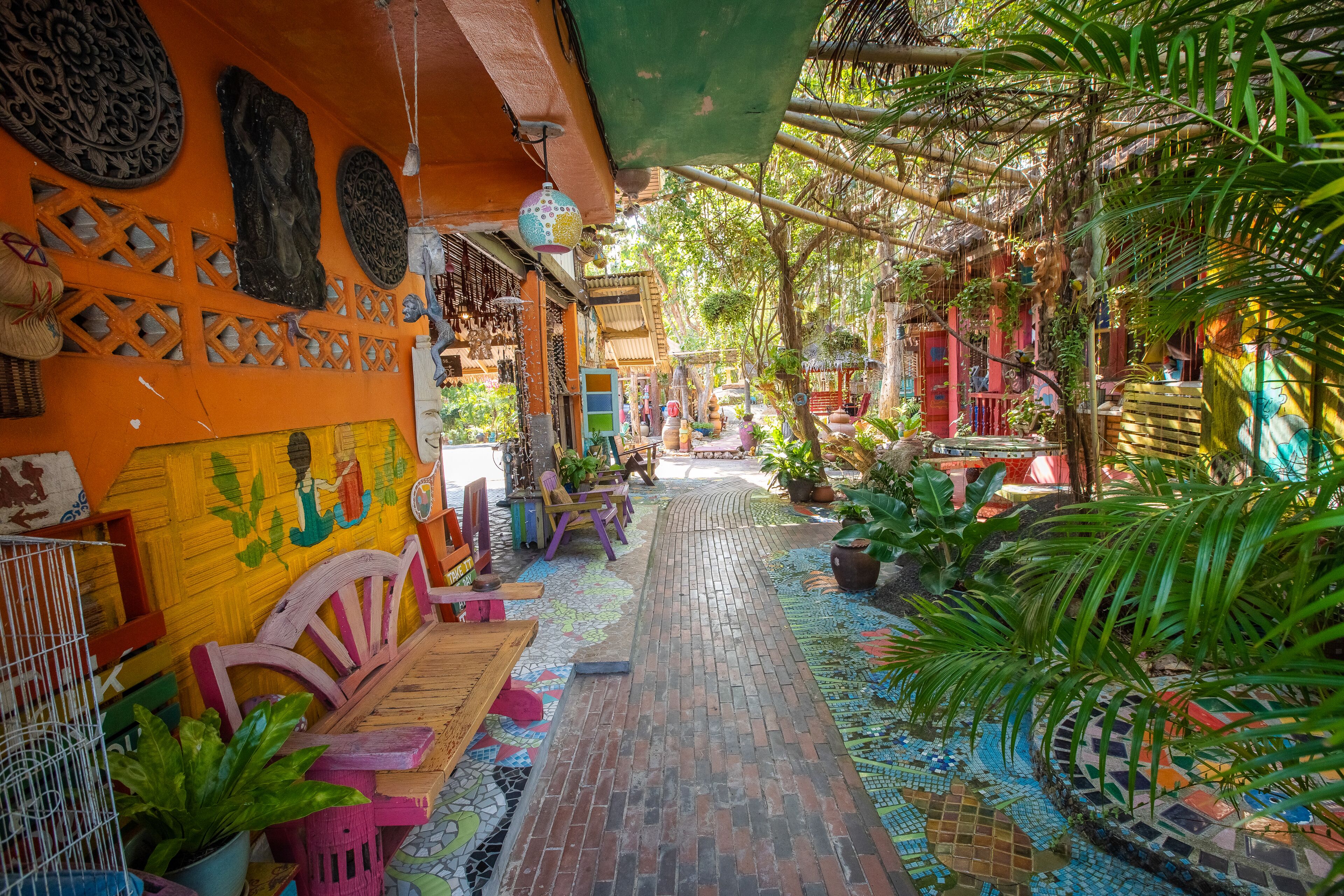 A courtyard with a tiled walkway, wooden benches, and potted plants.