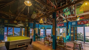 A pool table in a room with wooden flooring and colorful furniture. - Varinda Garden Resort (Koh Samui)