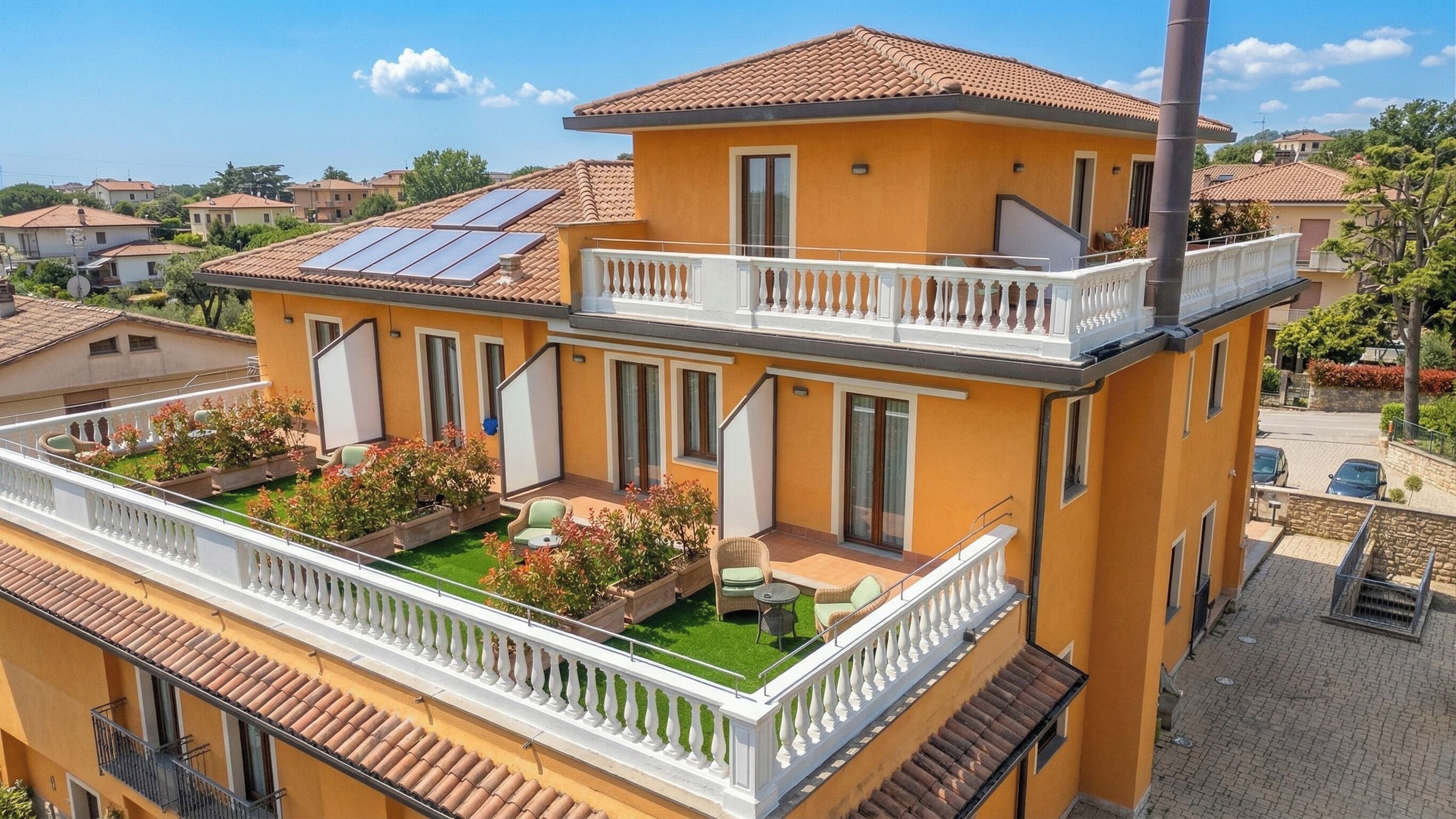 A two-story building with a balcony, solar panels, and a garden area.