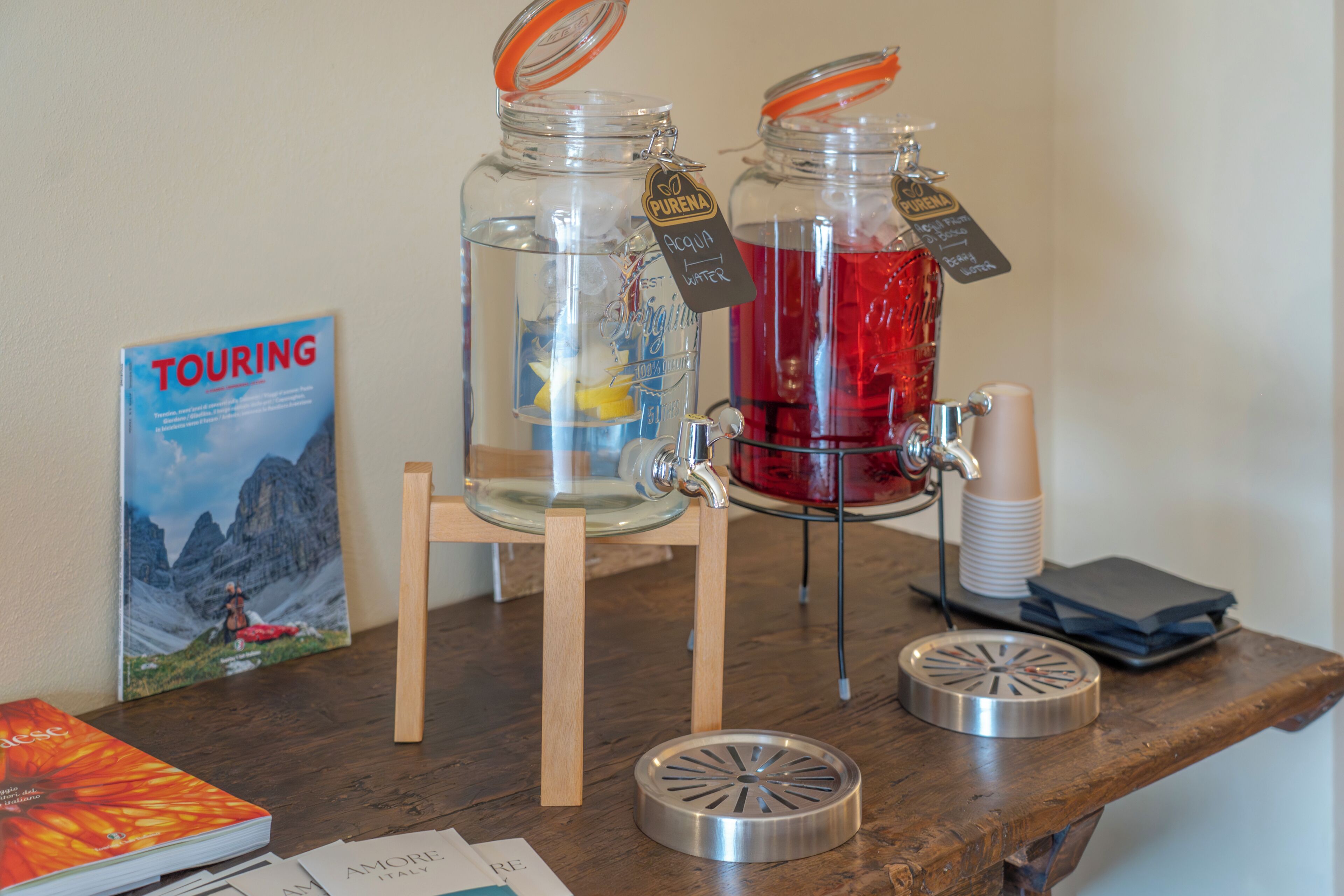 Two glass jars with water and juice, a book titled 'TOURING,' and a wooden chair.