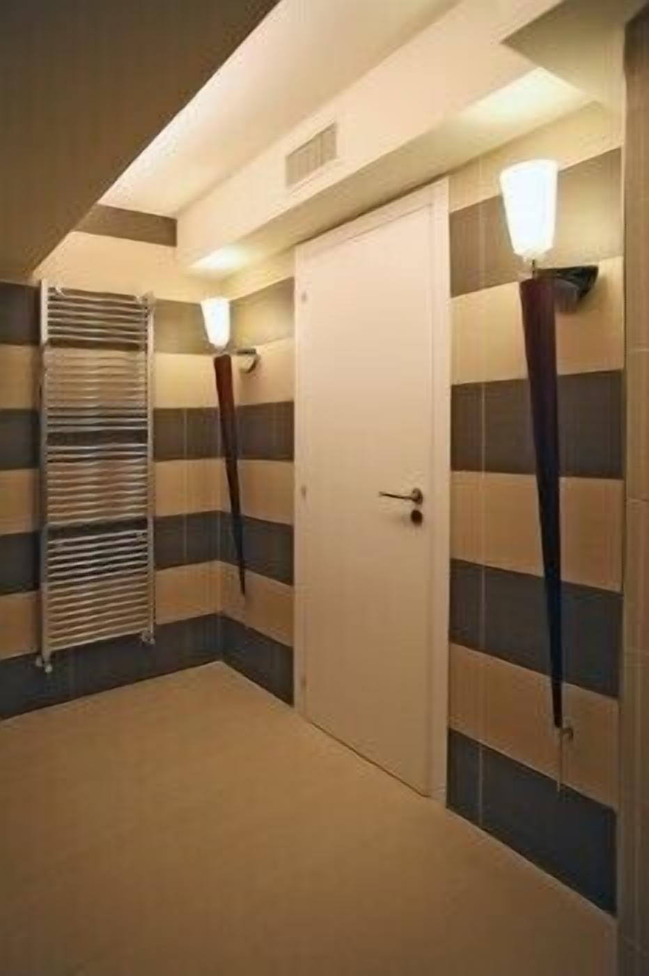 A hallway with a white door, striped walls, and a radiator.