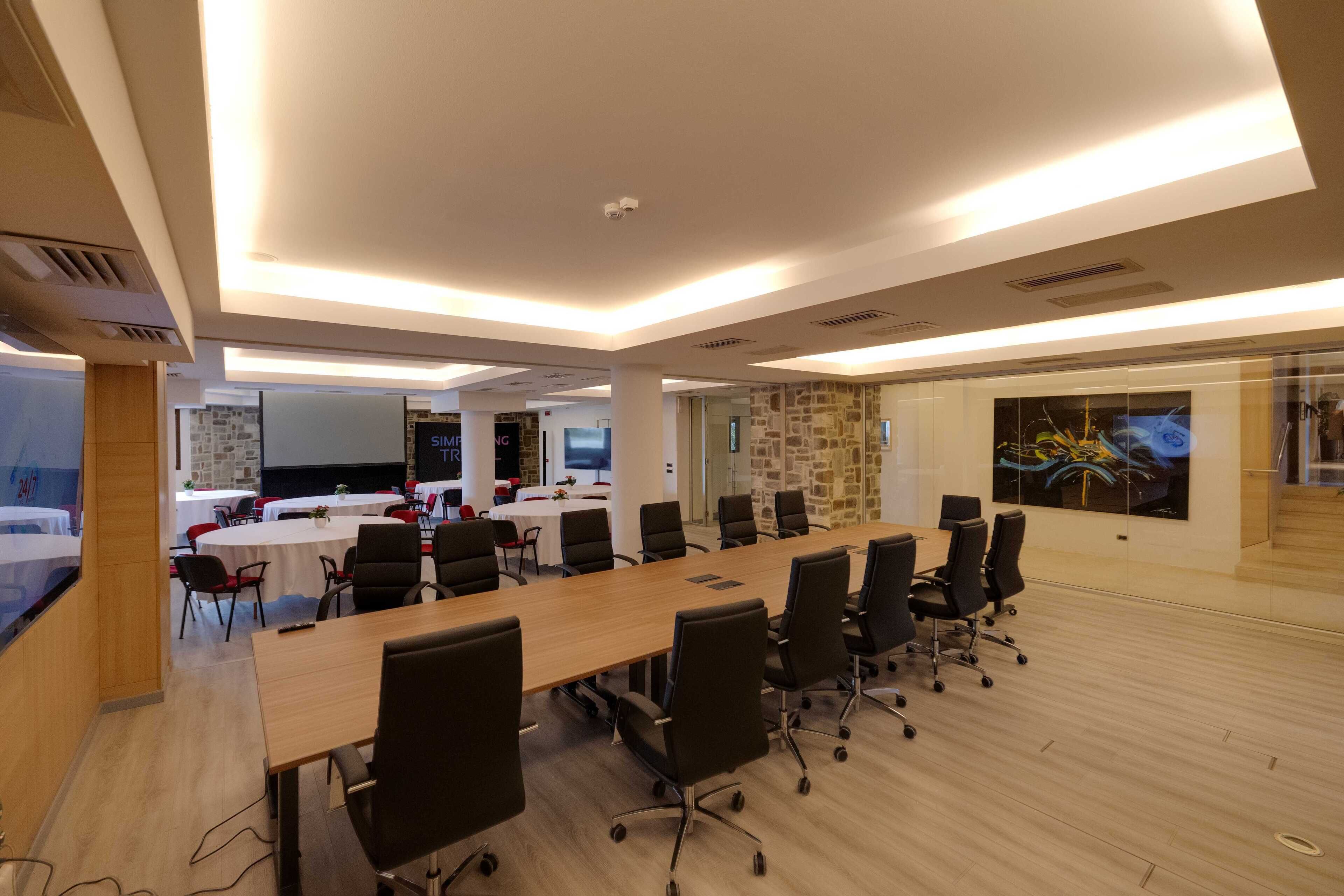 A modern conference room with a long table, black office chairs, and a stone accent wall.