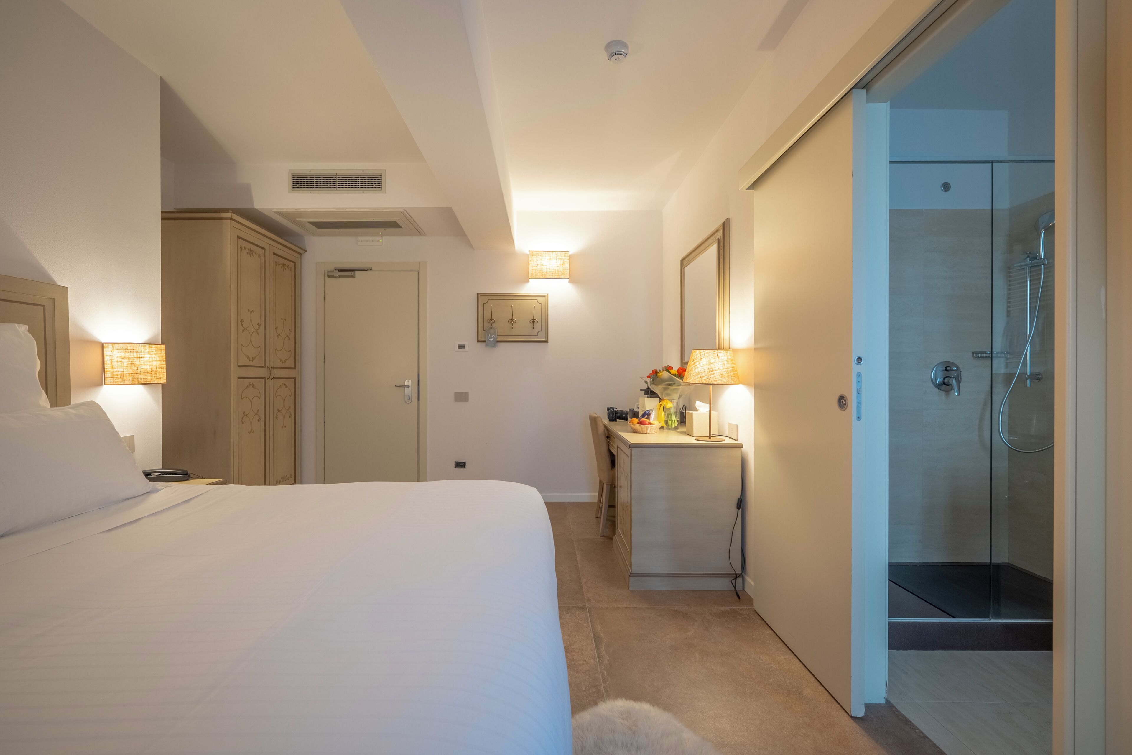 Ein Hotelzimmer mit Bett, Schreibtisch, Dusche und Kleiderschrank.