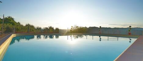 A clear swimming pool with a view of the surrounding landscape.