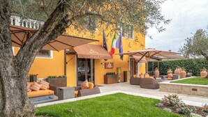 Un hotel con terraza al aire libre, un árbol y varias banderas.