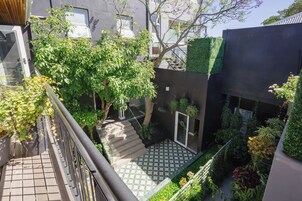 A multi-level outdoor area with a staircase, greenery, and a modern building facade.