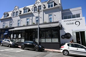 A boutique hotel with a classic architectural style, featuring a prominent sign for 'Boutique Hotel & Spa Cloud 9' and a 'Delune Spa & Hair' adjacent to it.