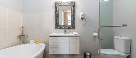 A modern bathroom with a freestanding bathtub, a vanity with a mirror, and a toilet.