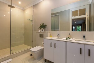 A modern bathroom with a glass-enclosed shower, a toilet, a sink with a mirror, and a cabinet.